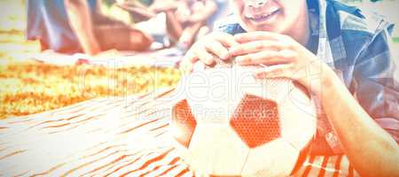 Smiling boy leaning on his football in picnic at park