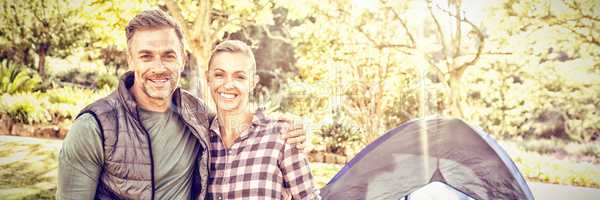 Couple smiling at camera while kids sitting in tent