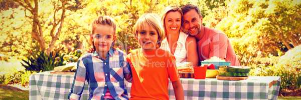 Happy family sitting at table in park