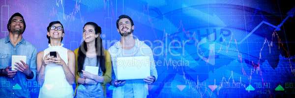 Composite image of smiling business people holding technology while looking up