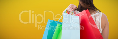 Composite image of rear view of brunette holding shopping bags