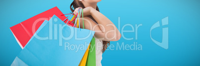 Composite image of brunette posing and holding shopping bags