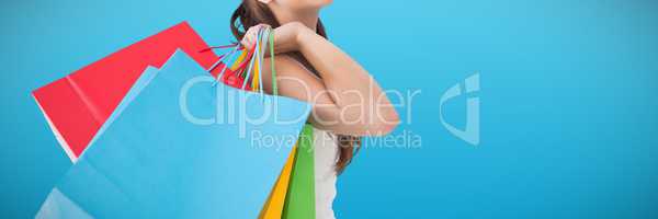 Composite image of brunette posing and holding shopping bags