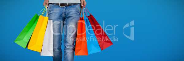 Composite image of low section of man carrying colorful shopping bag