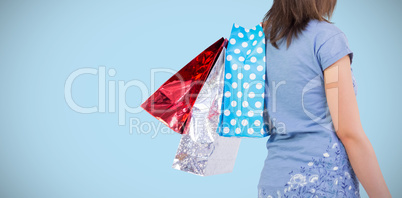 Composite image of rear view of young woman with shopping bags