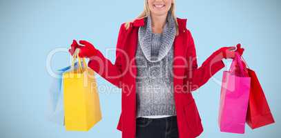 Composite image of blonde in winter clothes holding shopping bags