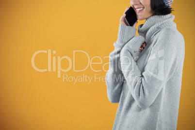 Composite image of woman in winter clothing talking on mobile phone