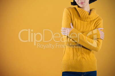 Composite image of woman in warm cloths standing with arms crossed against white background