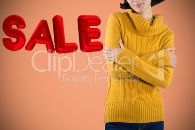 Composite image of woman in warm cloths standing with arms crossed against white background