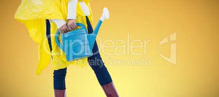 Composite image of woman in yellow raincoat holding an watering can
