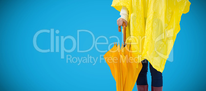 Composite image of woman in yellow raincoat holding an umbrella