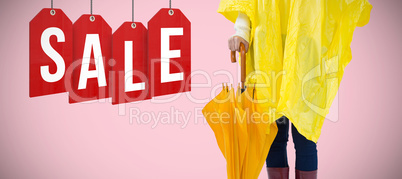 Composite image of woman in yellow raincoat holding an umbrella
