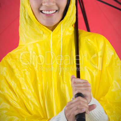 Composite image of woman in yellow raincoat holding an umbrella