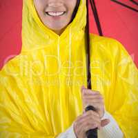 Composite image of woman in yellow raincoat holding an umbrella