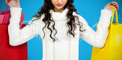 Composite image of woman with christmas hat holding colored shopping bags