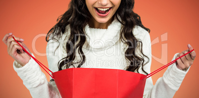 Composite image of happy woman with christmas hat opening red shopping bag