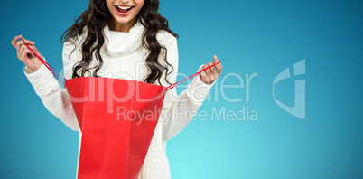 Composite image of happy woman with christmas hat opening red shopping bag