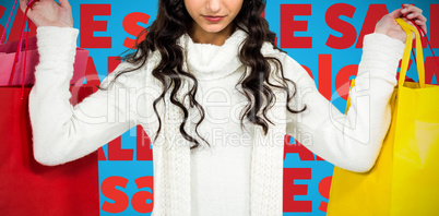 Composite image of woman with christmas hat holding colored shopping bags