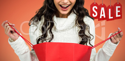 Composite image of happy woman with christmas hat opening red shopping bag