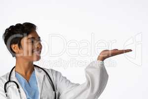 Smiling female doctor shows a copy space with her hand