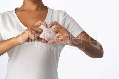 Women making heart shape with their fingers around pink ribbon