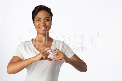 Smiling women making heart shape with their fingers around pink ribbon