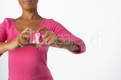 Women wearing pink shirt making heart with their fingers around pink ribbon