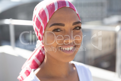 Portrait of smiling woman wearing scarf with breast cancer awareness