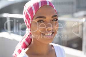Portrait of smiling woman wearing scarf with breast cancer awareness