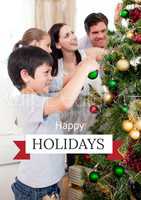 Happy Holidays text with family decorating tree