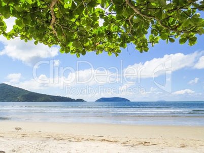Beach in sunny day with blue sea and island in the background.