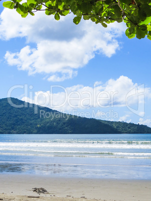 Beach in sunny day with blue sea and island in the background.
