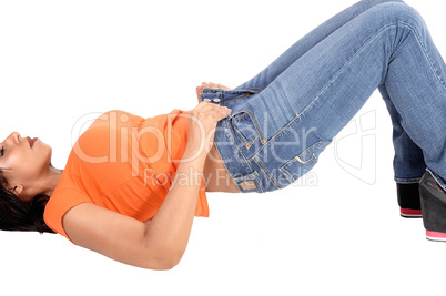 Young woman lying on floor putting jeans on