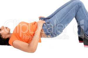 Young woman lying on floor putting jeans on