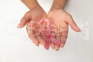 Two hands displaying pink ribbon for breast cancer awareness