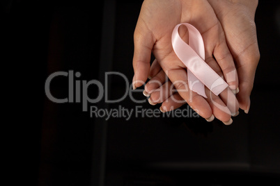 Hands presenting pink ribbon for breast cancer awareness