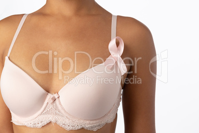 Mid section of woman in white bra with pink ribbon