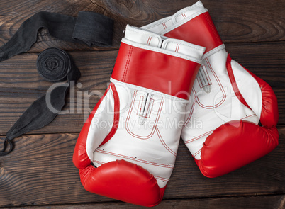 pair of red leather boxing gloves and elastic black bandage