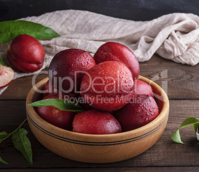 ripe red peaches in a wooden bowl on a table