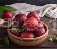 ripe red peaches in a wooden bowl on a table