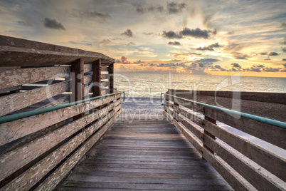 Boardwalk leading to the ocean at Vanderbilt Beach at sunset