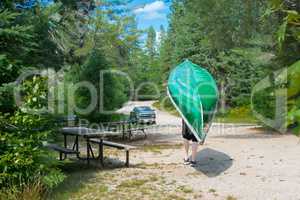 A man carries a canoe to the car