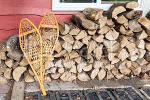 Snowshoes stand near the stacked firewood