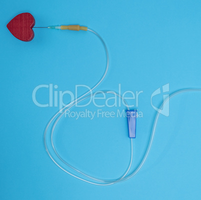 empty plastic dropper with needles and red heart on blue backgro