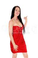 Beautiful woman standing in a red dress pointing finger