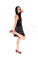 Woman standing in black dress holding up one leg