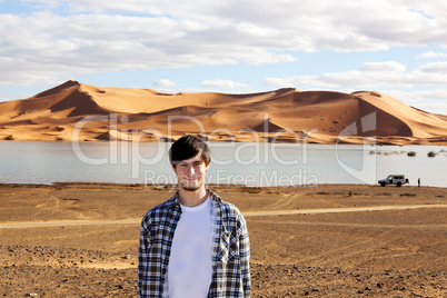 Young man in the desert at the lake with sand dunes in Morocco