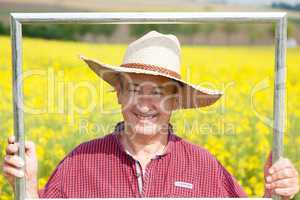 Farmer with photo frame is placed in canola field