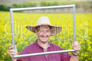 Farmer with photo frame is placed in canola field