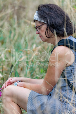 Woman is sitting in the tall grass